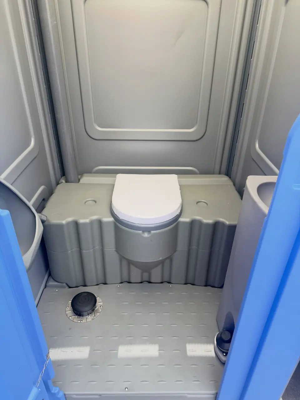 Gray porta potty interior with seat and non-slip floor