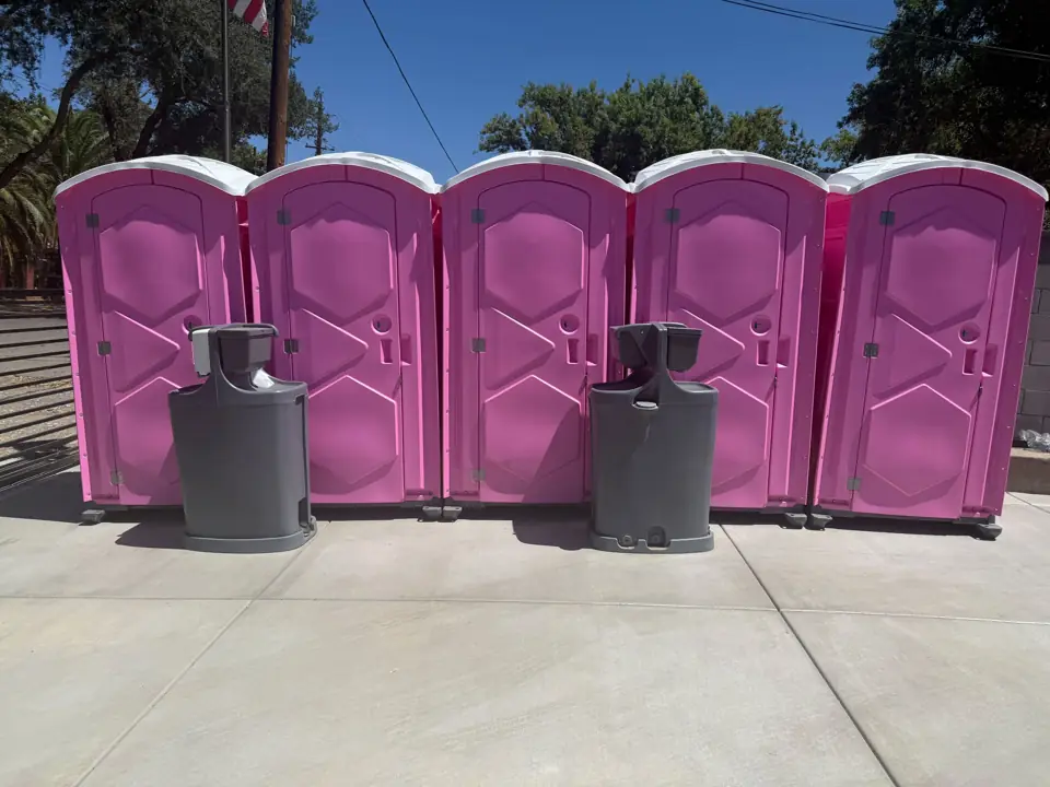Row of pink porta potties with two hand wash stations
