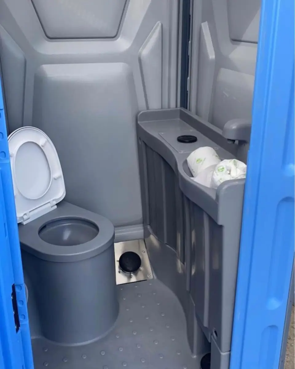 Gray portable toilet interior with a toilet and a small built-in sink