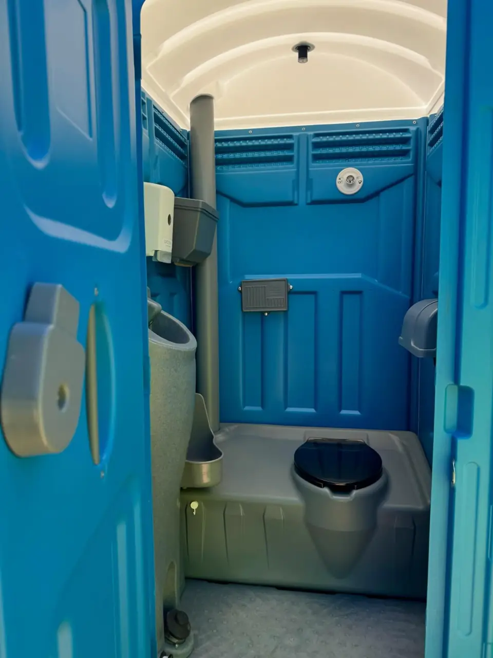 Inside a blue portable toilet with a built-in hand sink