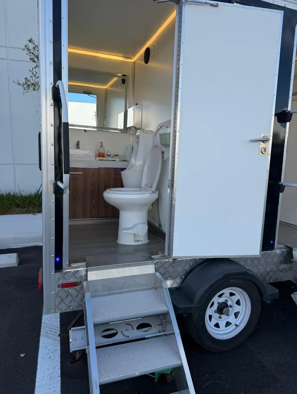 Restroom trailer with door open and metal steps down to the ground