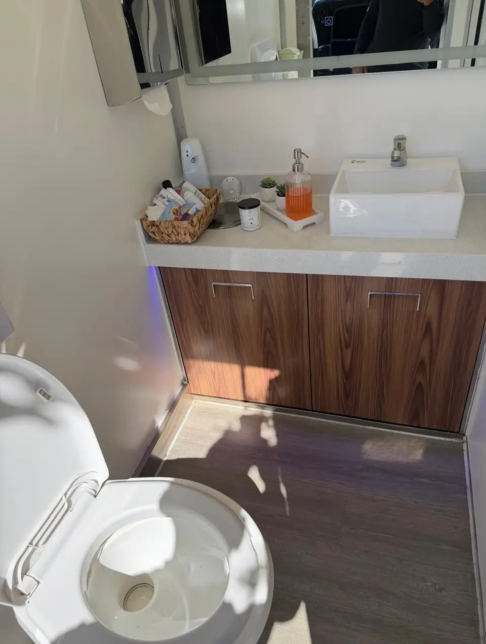 Restroom trailer wood-look vanity with sink and amenities basket