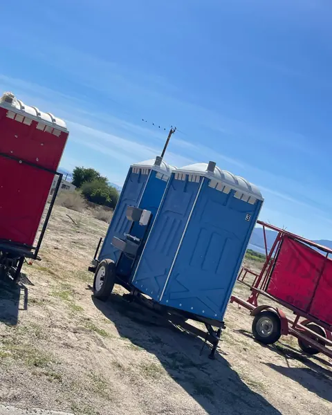 Towable portable toilet trailer parked on a dirt job site