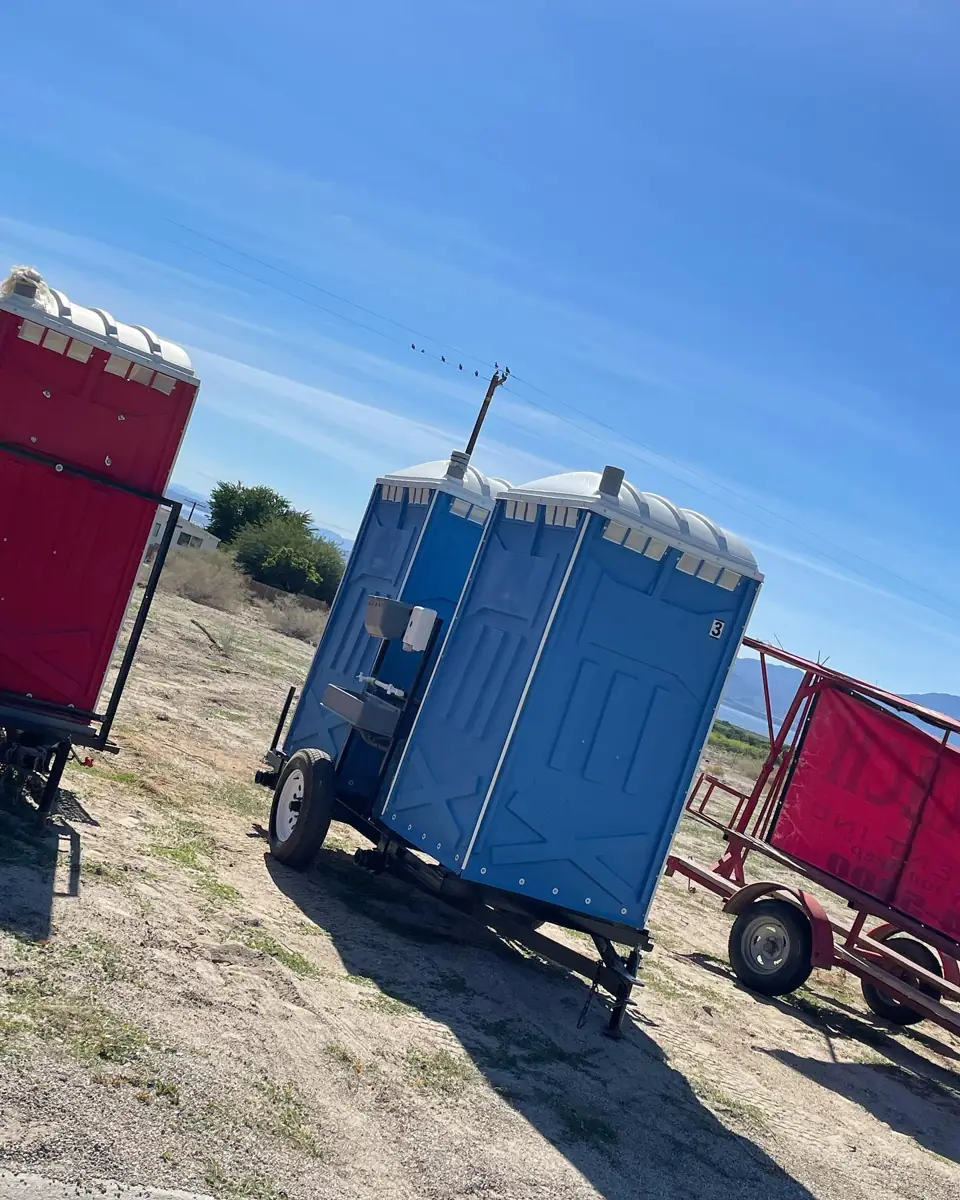 Towable portable toilet trailer parked on a dirt job site