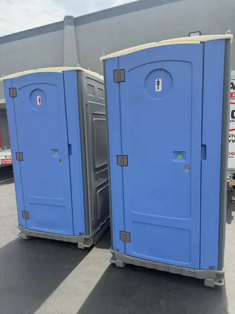 Two blue porta potties in a parking lot